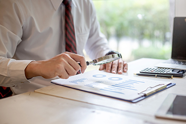 Businessman using magnifying glass to look at financial data gra Businessman using magnifying glass to look at financial data graph.