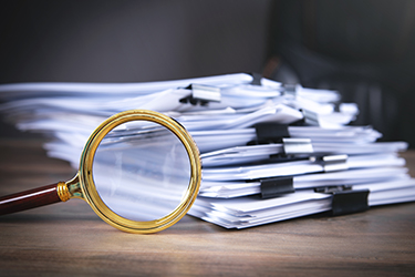 Stack of documents and magnifying glass on the table. Stack of documents and magnifying glass on the table.