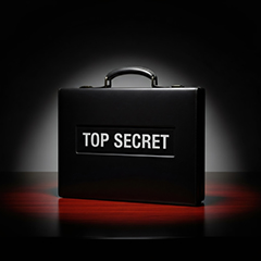 Top secret briefcase in a spotlight on a dark wooden table. 
