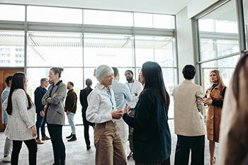 Diverse professionals networking at a business event in a modern office building Diverse group of professionals networking, engaging in conversations, and building business relationships at a corporate event.