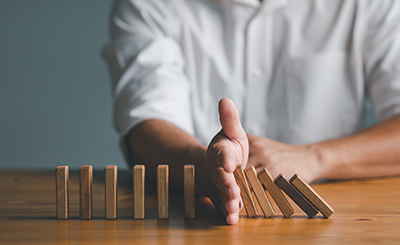 Risk and Strategy in Business, Hand stopping wooden block domino business crisis effect or risk protection concept, prevention and development to stability. Risk and Strategy in Business, Hand stopping wooden block domino business crisis effect or risk protection concept, prevention and development to stability.