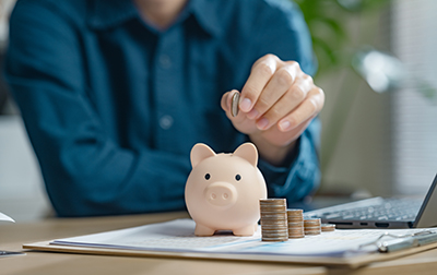 A person is putting coins into a piggy bank. retirement, earnings, financial, loan, economic, finance, wealth, piggy bank, assurance, future. A person is putting coins into a piggy bank. Concept of saving money and being financially responsible.